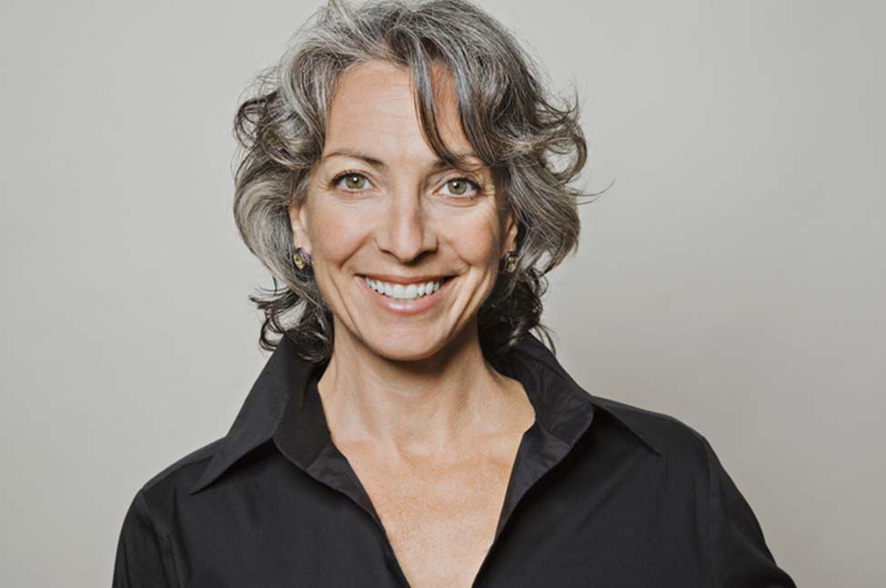 Woman smiles directly at camera, shoulders visible