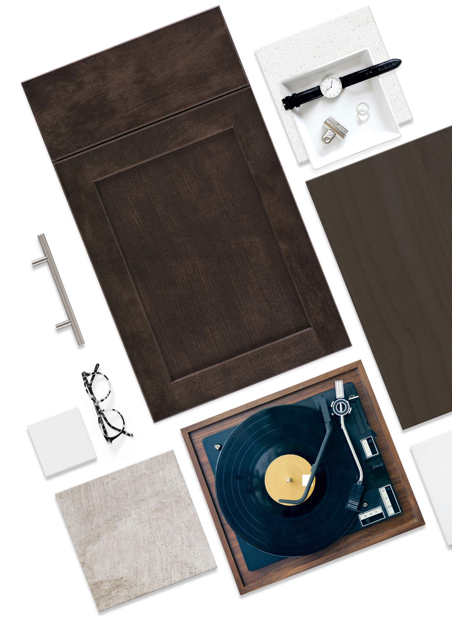 Dark recessed wood cabinet door lies flat among material samples and accessories