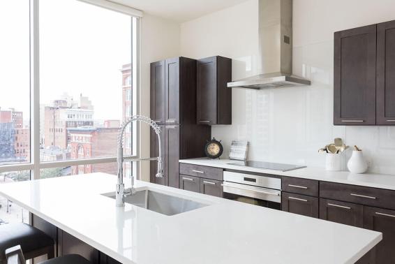 Kitchen island with integrated sink and tall gooseneck faucet gleams in sunlight