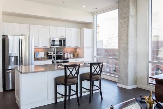 Kitchen island with built-in sink and two barstools anchors an open-plan modern kitchen