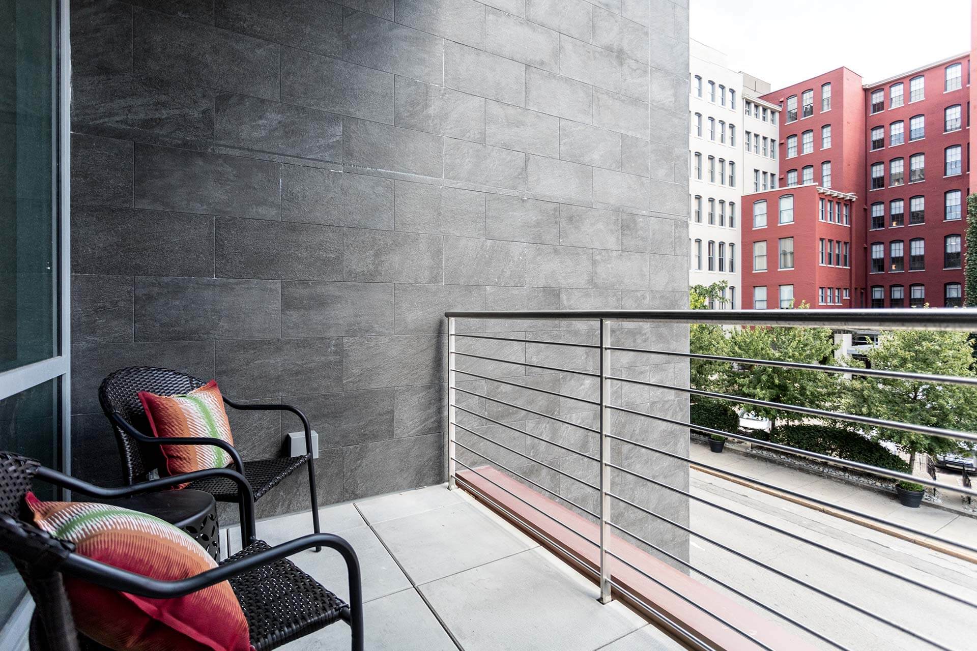 Balcony chairs sit facing outward on a tiled balcony