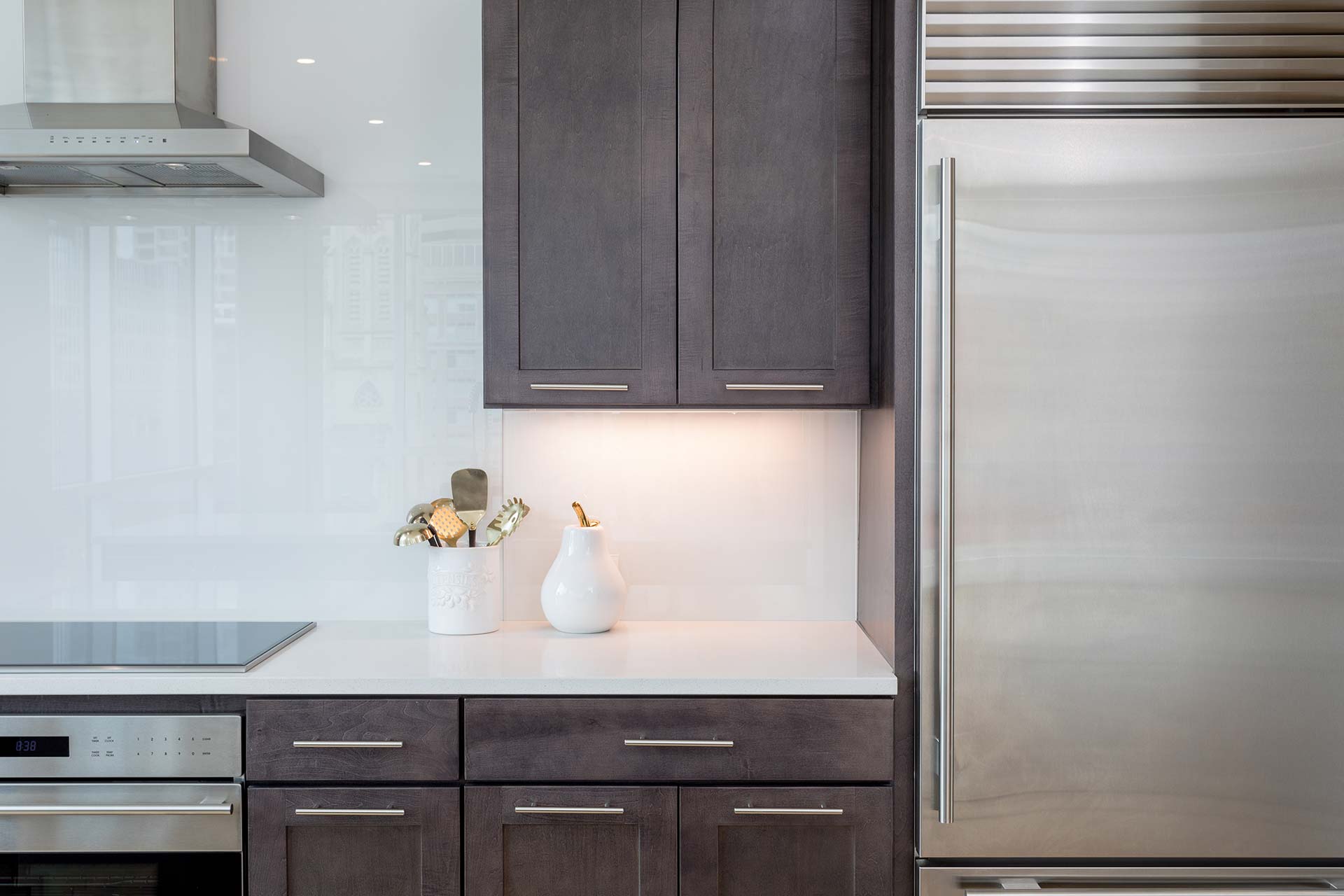 Dark wood cabinets frame a white countertop that holds a ceramic utensil holder and white pitcher