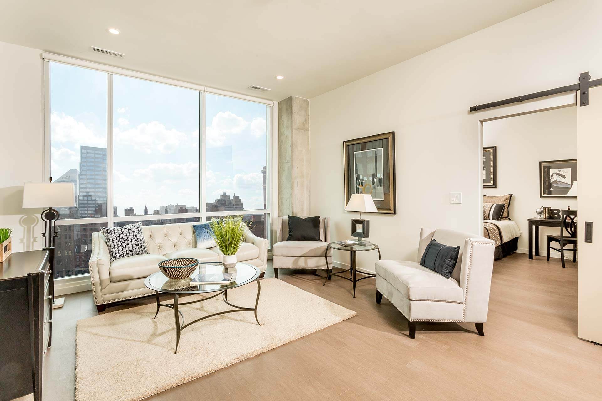 A tufted white sofa faces a glass coffee table