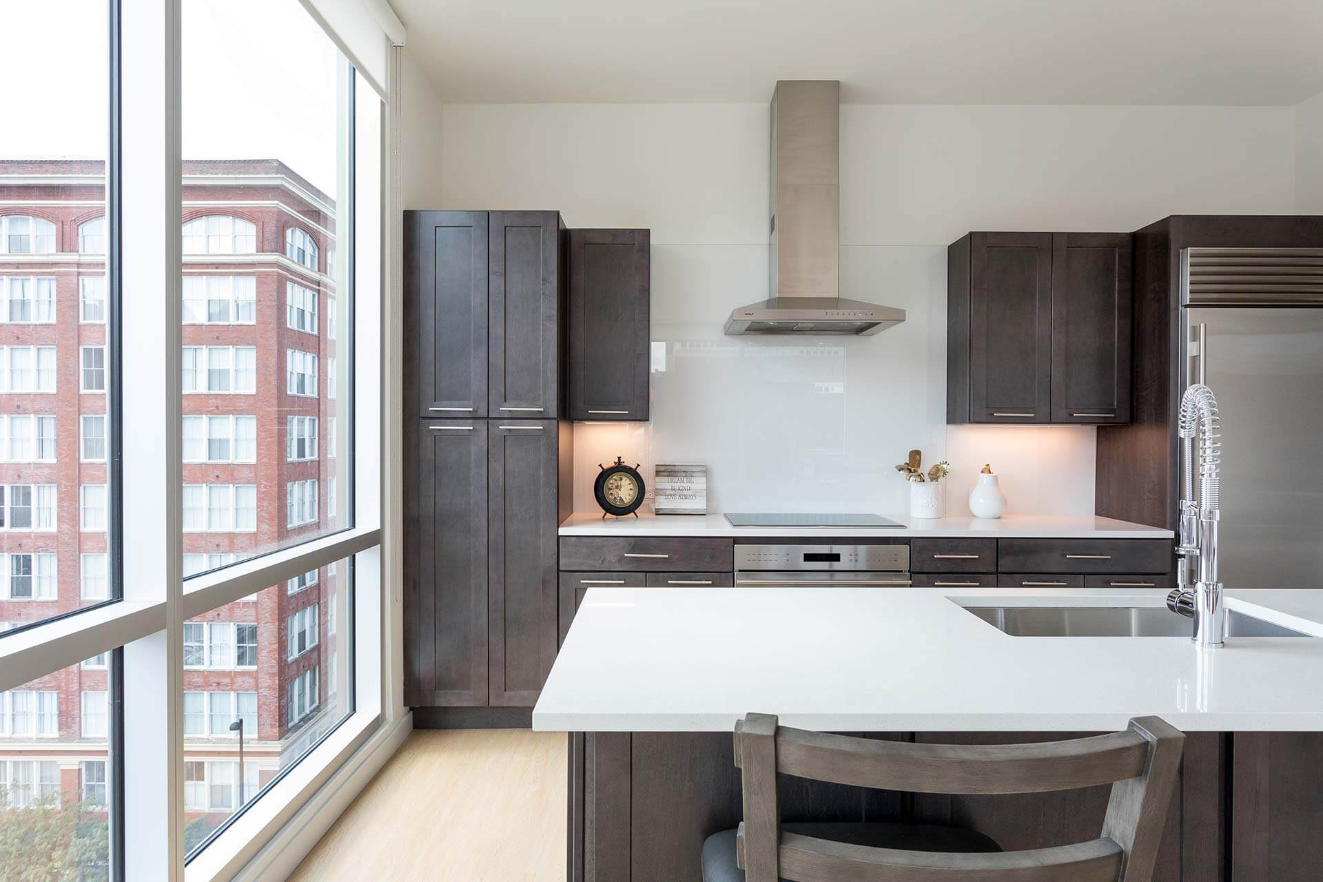 Dark wood kitchen cabinets frame a white island with a chrome spring‑neck faucet and undermount sink