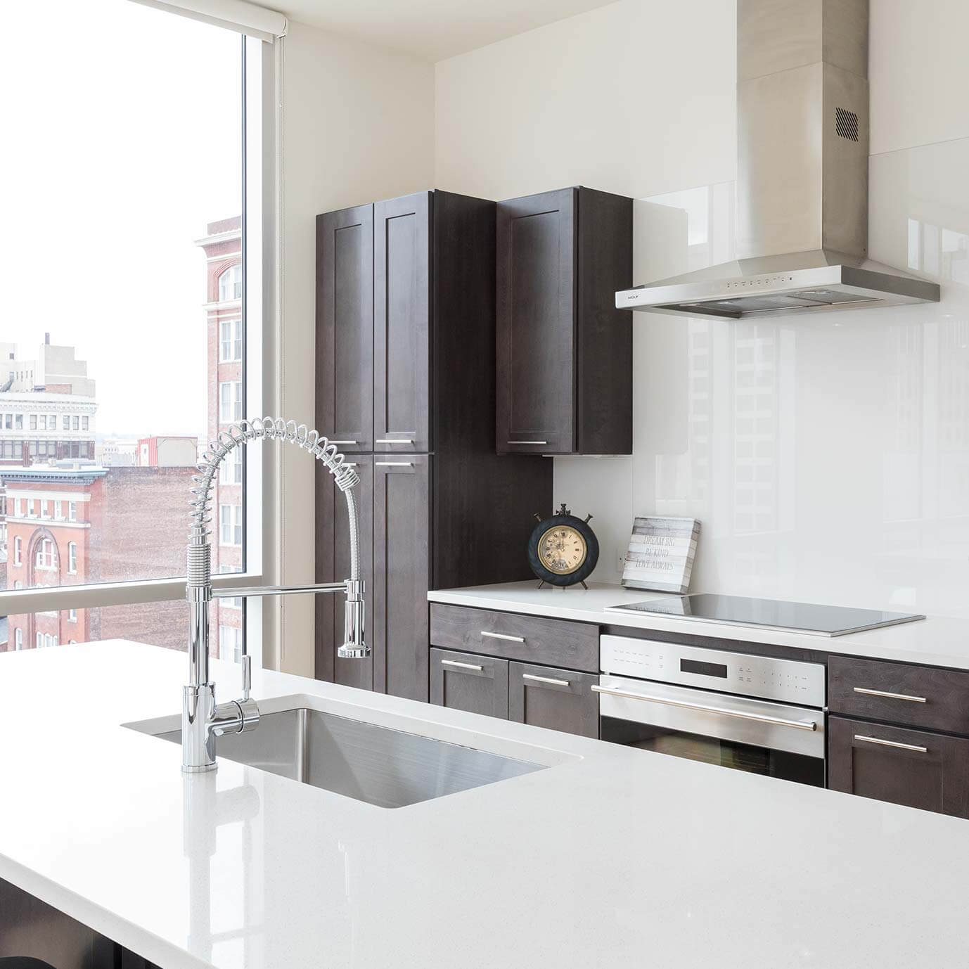 Chrome spring kitchen faucet arches over a rectangular undermount sink on a white quartz island