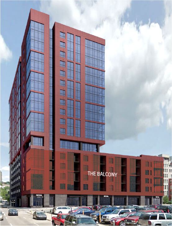 A red-glass high-rise towers over a street, featuring a mid-rise podium with balconies, ground-floor retail and a crowded parking lot under a cloudy sky
