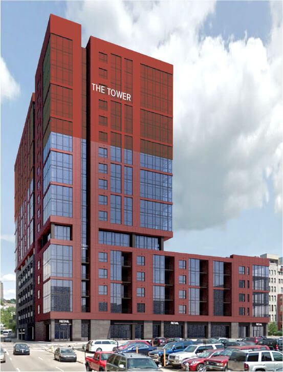 A red high-rise building rises above a street of parked cars under a cloudy sky.